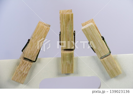 Close up wooden clothespins clipping a paper bag on soft pastel background. Minimal still life composition with copy space, household tool and stationery concept. Close up wooden clothespins clipping a paper bag on soft pastel background. Minimal still life composition with copy space, household tool and stationery concept. 139023136