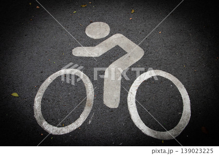 White bicycle lane symbol painted on asphalt road surface. Cycling path marking for urban transportation, eco-friendly travel and traffic safety concept. Top view with copy space. 139023225