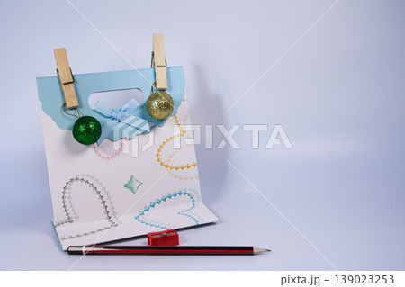 Decorative gift bag with ornaments, pencil and sharpener isolated on white background. Creative stationery still life with copy space for education, design or celebration concept. 139023253