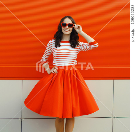 Beautiful happy young woman posing in red heart shaped sunglasses, skirt Beautiful happy young woman posing in red heart shaped sunglasses, skirt 139023288