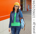 Happy woman student with eyeglasses, backpack standing in the city 139023294