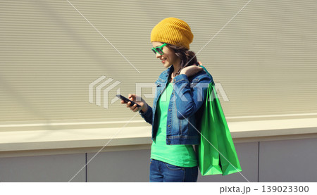 Beautiful happy young woman holding phone with colorful shopping bag 139023300