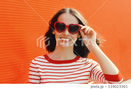 Beautiful happy young woman posing in red heart shaped sunglasses 139023301