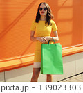 Beautiful young woman full-length posing with shopping bags in the city 139023303