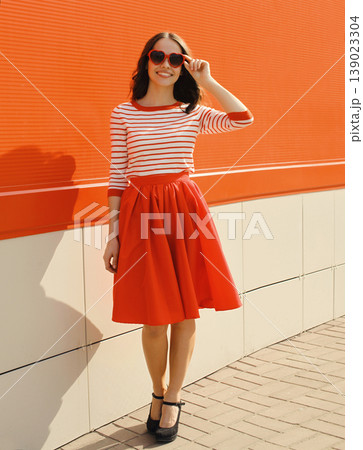 Beautiful happy young woman posing in red heart shaped sunglasses, skirt 139023304