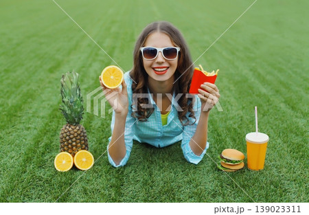 Happy young woman chooses unhealthy or healthy food with burger fast food 139023311