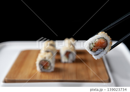 Hand Taking Sushi with Chopsticks. Japanese Cuisine Sushi Being Picked with Chopsticks. Hand Taking Sushi with Chopsticks. Japanese Cuisine Sushi Being Picked with Chopsticks. 139023734