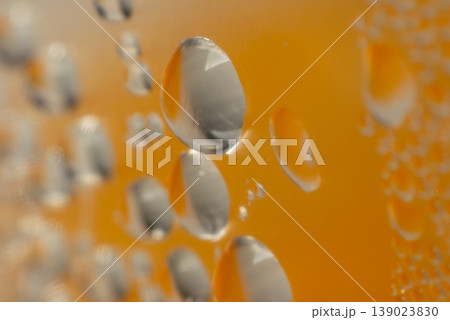 Macro water droplets on cold beer glass with warm golden tone background refreshing beverage detail condensation surface abstract texture closeup 139023830