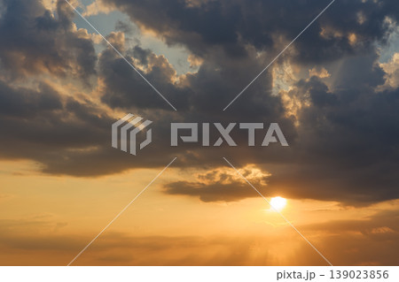 日没の太陽が雲の隙間から輝く夕暮れのグラデーション 139023856