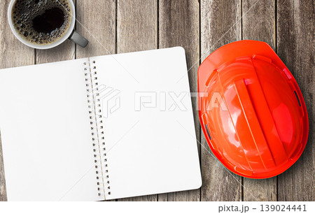 Red engineer safety helmet and blank notebook with coffee overhead view. 139024441