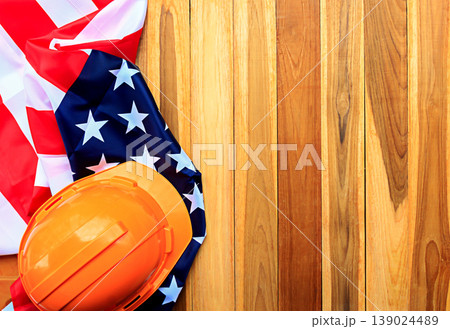 Top view with orange safety helmet and usa flag on wood table background. Top view with orange safety helmet and usa flag on wood table background. 139024489