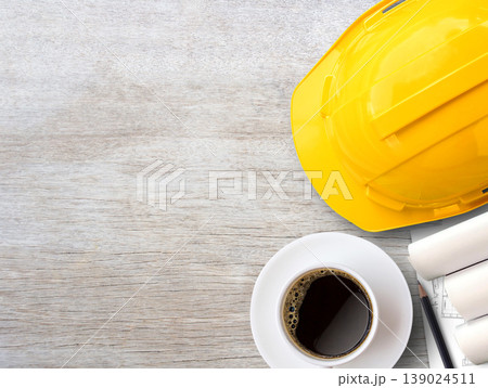 Yellow safety helmet or hard hat and construction paper plans on wood table background. 139024511