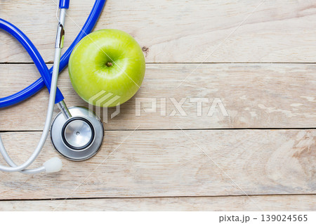 Top view green apple with blue stethoscope on wood table background. Top view green apple with blue stethoscope on wood table background. 139024565