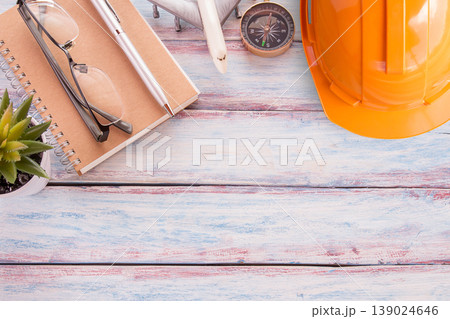 Flat lay photo with safety helmet,notebook,glasses,airplane toy,compass, pen and cuctus flower on wooden table background. Flat lay photo with safety helmet,notebook,glasses,airplane toy,compass, pen and cuctus flower on wooden table background. 139024646