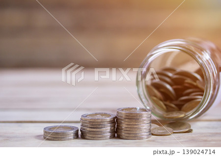 Close up saving money into a glass jar for cash in future investment. Close up saving money into a glass jar for cash in future investment. 139024714