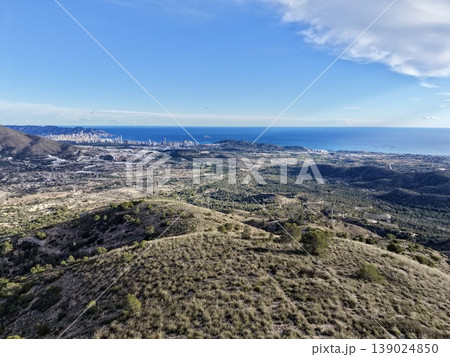 Coastline With City, Lush Seaside Ridge Descending Towards Tranquil Blue Horizon With Distant City Clusters 139024850