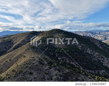 Barren Ridge Under Dramatic Cloudy Skies, Remote Ridge Surrounded By Sparse Plants And Rugged Rocks 139024887