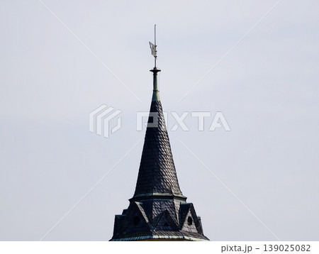Slate Tower Cuts Through Pale Daytime Sky. Weathered Roof With Sleek Geometric Design And Airy Backdrop 139025082