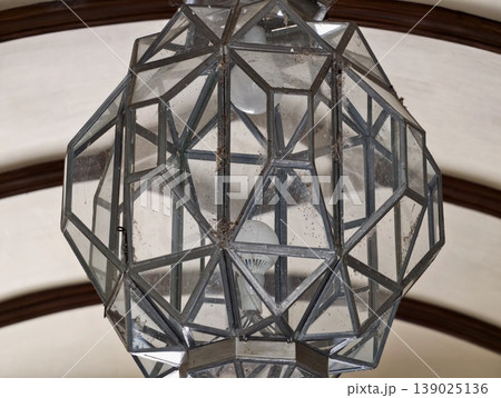 Decorative Chandelier Made Of Geometric Glass Panels And Metallic Accents Hanging From High Vaulted Ceilings Decorative Chandelier Made Of Geometric Glass Panels And Metallic Accents Hanging From High Vaulted Ceilings 139025136