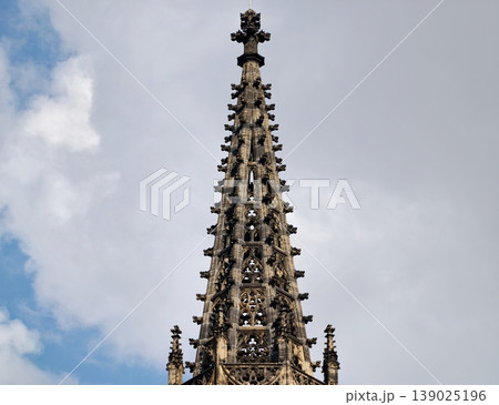 Intricate Gothic Architectural Design. Majestic Spire With Detailed Lace Patterns Against Cloudy Sky Intricate Gothic Architectural Design. Majestic Spire With Detailed Lace Patterns Against Cloudy Sky 139025196