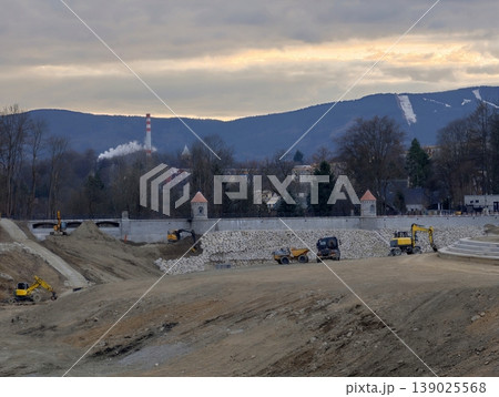 Site With Heavy Machinery And Workers. Village Church Backdrop With Construction Site And Mountain Scenery 139025568