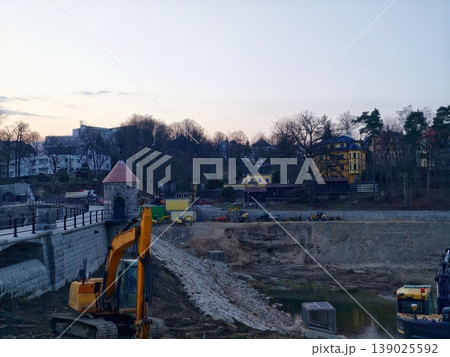 Construction Zone During Evening With Heavy Machinery Creating Embankments And Muddy Paths 139025592