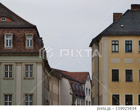 Peaceful European Street View Featuring Tiled Rooftops And Softly Toned Building Facades Under Cloudy Skies 139025634