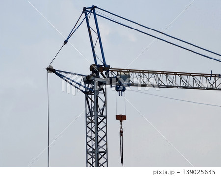 Modern Crane Under Cloudy Sky Viewed. Construction Site With Crane Silhouetted Against Gray Sky 139025635