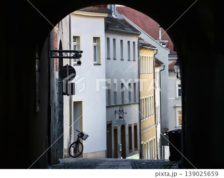 Urban Bike Scene. Narrow Street With Bicycle. Shadowed Alleyway Featuring Leaning Bicycle And Stone Stairs 139025659