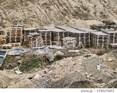 Wooden Pallets Discarded. Scene Depicting Salvageable Materials In Rugged Industrial Quarry Environment Wooden Pallets Discarded. Scene Depicting Salvageable Materials In Rugged Industrial Quarry Environment 139025663