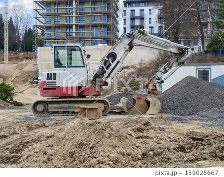 Construction Machine Excavates Earth. Construction Vehicle Prepares Soil Amidst Building Developments Construction Machine Excavates Earth. Construction Vehicle Prepares Soil Amidst Building Developments 139025667