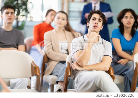 Young guy listening to lecture with a teacher standing in background 139026226