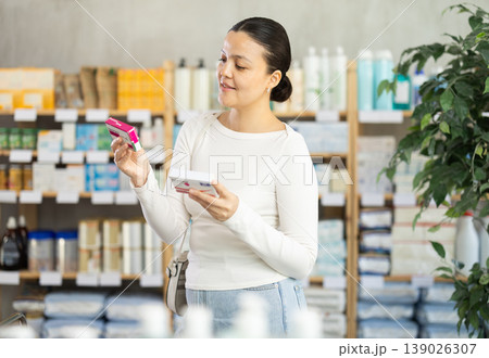 Female customer examining boxes of paracetamol in drugstore Female customer examining boxes of paracetamol in drugstore 139026307