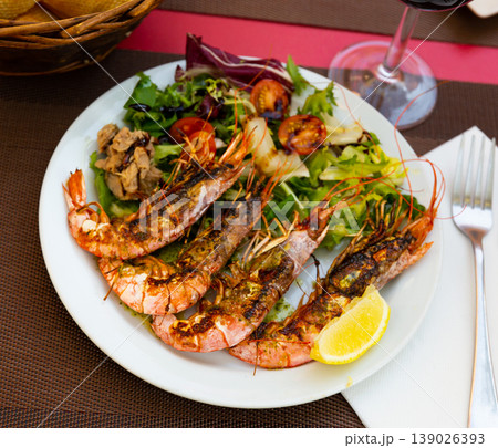 Seafood dish. Tasty grilled shrimp served with vegetables and lemon Seafood dish. Tasty grilled shrimp served with vegetables and lemon 139026393