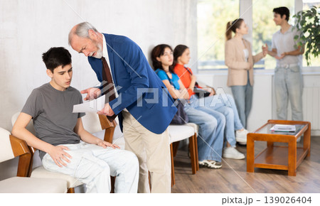 Mature male HR specialist conducts brief interview with guy applicant, queue in background Mature male HR specialist conducts brief interview with guy applicant, queue in background 139026404