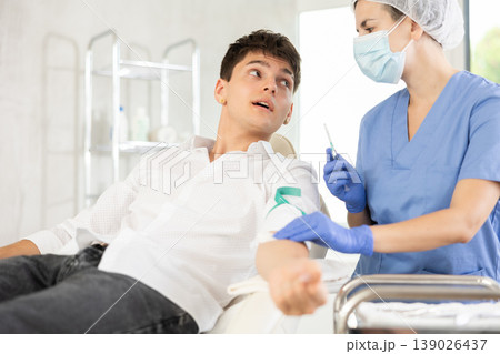 Young man having vein injection lying on clinical chair 139026437