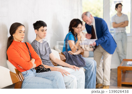 Young people sitting in a queue while manager talking with visitor Young people sitting in a queue while manager talking with visitor 139026438