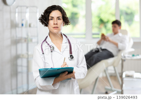Portrait shot of female doctor holding clipboard in hand while standing in medical esthetic clinic 139026493
