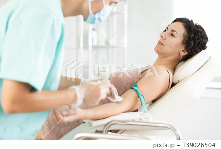 Male anesthesiologist injecting anesthetic into vein on her arm with syringe in cosmetology clinic Male anesthesiologist injecting anesthetic into vein on her arm with syringe in cosmetology clinic 139026504