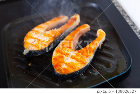 There are two pieces of broiled salmon steaks in square black frying pan There are two pieces of broiled salmon steaks in square black frying pan 139026527