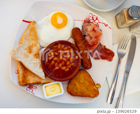 English breakfast with beans, fried egg, bacon, sausage, toasts and hash brown 139026529