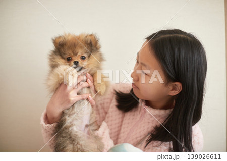 家で可愛いポメラニアンの子犬と遊んでいる女子中学生の様子 139026611