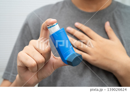 Asthma and chronic obstructive pulmonary disease COPD, Asian young man using metered dose inhaler MDI. 139026624