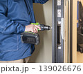 The technician installs a smart electronic lock on the front door. 139026676