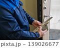 The technician installs a smart electronic lock on the front door. 139026677