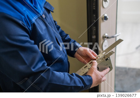 The technician installs a smart electronic lock on the front door. 139026677