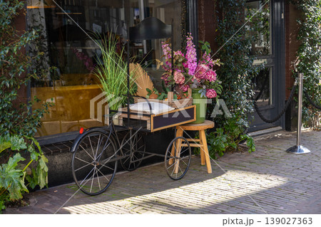 Decorative vintage style cart with flowers and plants outside cozy cafe entrance 139027363