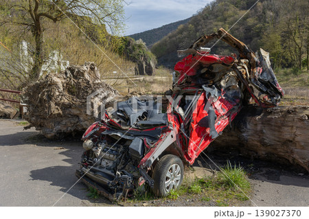 Severely damaged crushed car wreck after accident with debris and fallen tree trunk 139027370