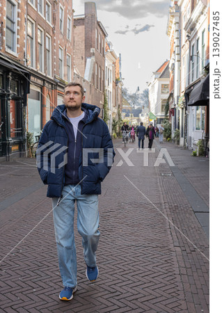 Man walking through historic european street with architecture and pedestrians urban travel concept Man walking through historic european street with architecture and pedestrians urban travel concept 139027485