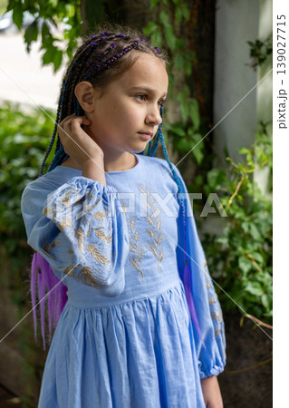 Close-up portrait of a young girl with braided hair in soft outdoor light.  139027715